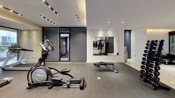 Un gimnasio moderno con equipo de cardio, estantes para pesas y un espejo.