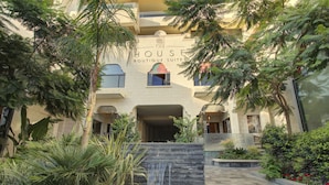 Un edificio con un letrero que dice "The House Boutique Suites" y una pequeña cascada en el patio.