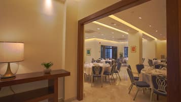 A hotel dining area with multiple tables and chairs, a lamp, and a potted plant.