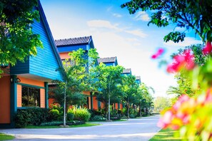 A row of modern, multi-story buildings with a uniform architectural style, featuring flat roofs and a mix of blue and orange facades. - Pailin Resort (Trat)