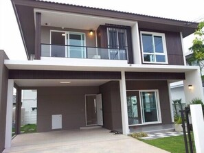 A modern two-story house with a covered patio, large windows, and a balcony. - Maximum Land & House with WiFi (Udon Thani)