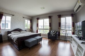 A bedroom with a wooden bed, a chair, a TV, and a window with curtains. - Maximum Land & House with WiFi (Udon Thani)