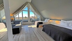 Una habitación de hotel moderna con cama de altillo, sofá y balcón con vistas.