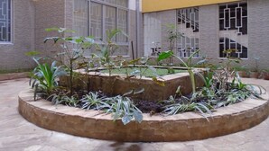 A courtyard with a circular garden bed surrounded by a low brick wall. - Tawala Homes (Nairobi)