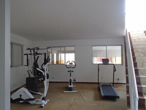 Un gimnasio en casa con equipo de ejercicio, incluyendo una cinta de correr, bicicleta estática y máquinas de pesas.