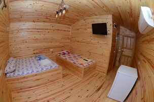 Una cabaña de madera con dos camas, un televisor y un refrigerador.