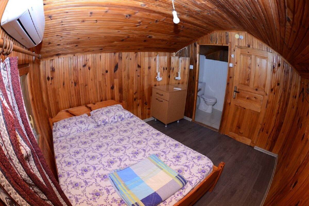Ein Zimmer mit Holzwandverkleidung, einem Bett, einer Kommode, einem Spiegel und einer Tür zu einem Badezimmer.