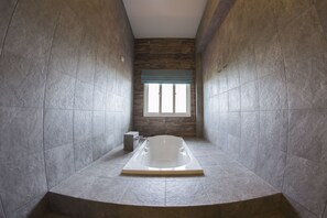A modern bathroom with a freestanding bathtub, stone walls, and a window with a view. - Maximize Brand New House (Udon Thani)