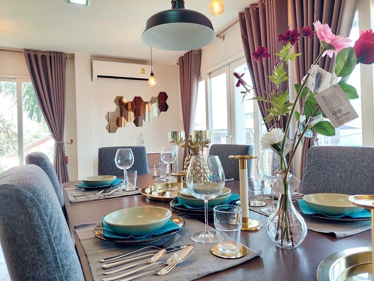 A dining table set with blue plates, gold cutlery, and a vase with flowers.