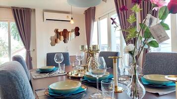 A dining table set with blue plates, gold cutlery, and a vase with flowers.