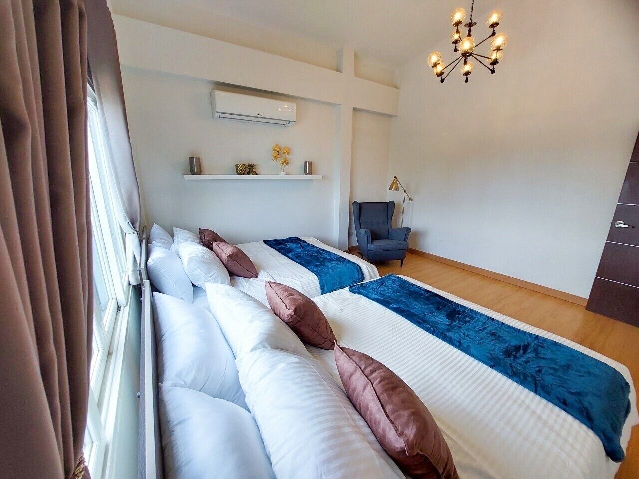 Une chambre d’hôtel avec deux lits, une chaise, un bureau et un lustre.