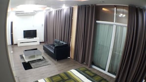 A living room with a sofa, TV, and curtains. - Maximum Luxury Apartment (Udon Thani)