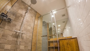 A modern bathroom with a shower, wooden vanity, and a glass-enclosed shower area. - Maximum Luxury Apartment (Udon Thani)