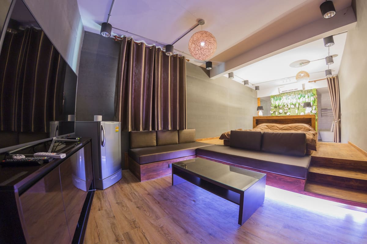 Una sala de estar moderna con sofá, mesa de centro y una zona de cocina con refrigerador.