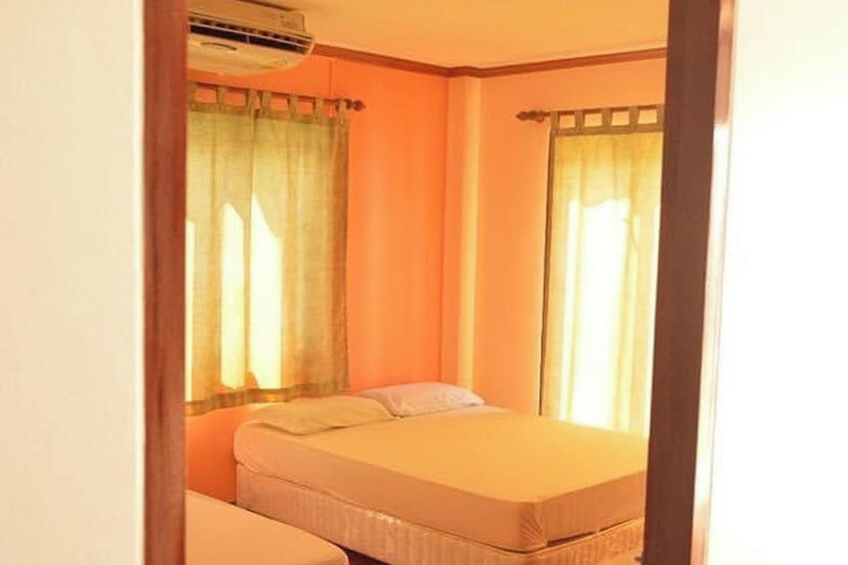 A room with two beds, a ceiling fan, and an air conditioning unit.