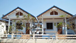 Dos casas blancas con techos azules y contraventanas de madera, que incluyen un porche cubierto y una pequeña piscina.