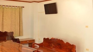 Una habitación con una mesa de comedor de madera, un banco de madera, un televisor montado en la pared y un techo con diseño decorativo.