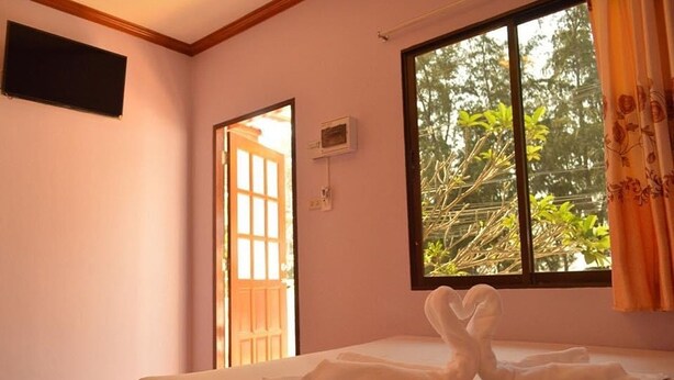 Una habitación con una cama, una ventana con cortinas y una puerta.