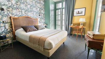 Habitación de hotel ordenada con cama, una silla, una mesa y ventana con cortinas.