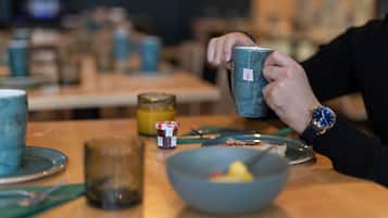 A dining table with a bowl of food, a jar of jam, and a mug.