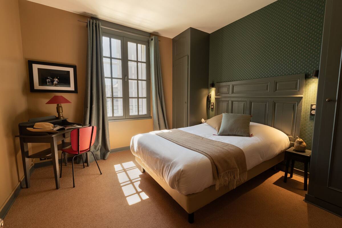 A neatly arranged bedroom with a bed, a desk, and a chair.