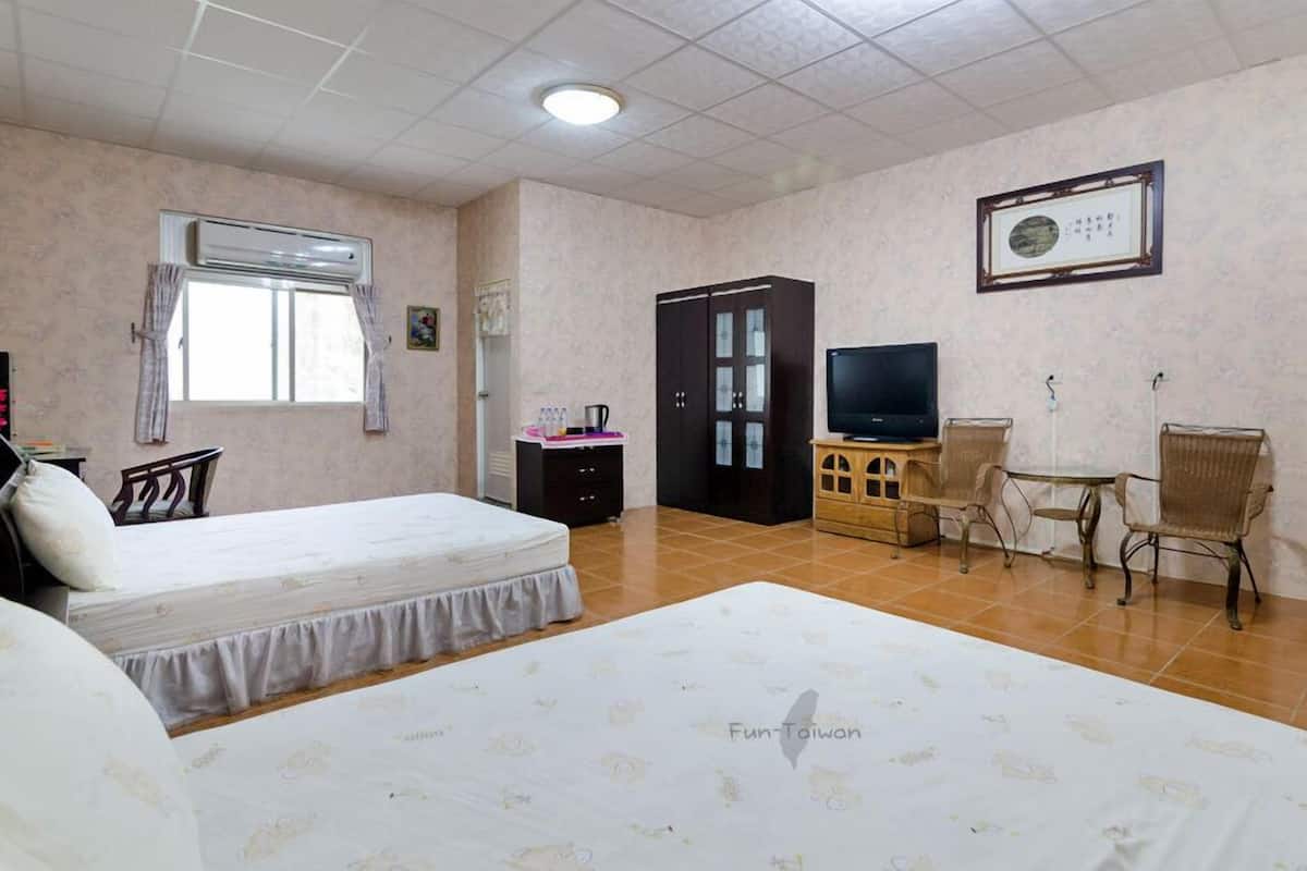 Una habitación de hotel con dos camas, un televisor, un escritorio con silla y un armario.