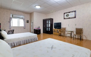 Una habitación de hotel con dos camas, un televisor, un escritorio con silla y un armario.