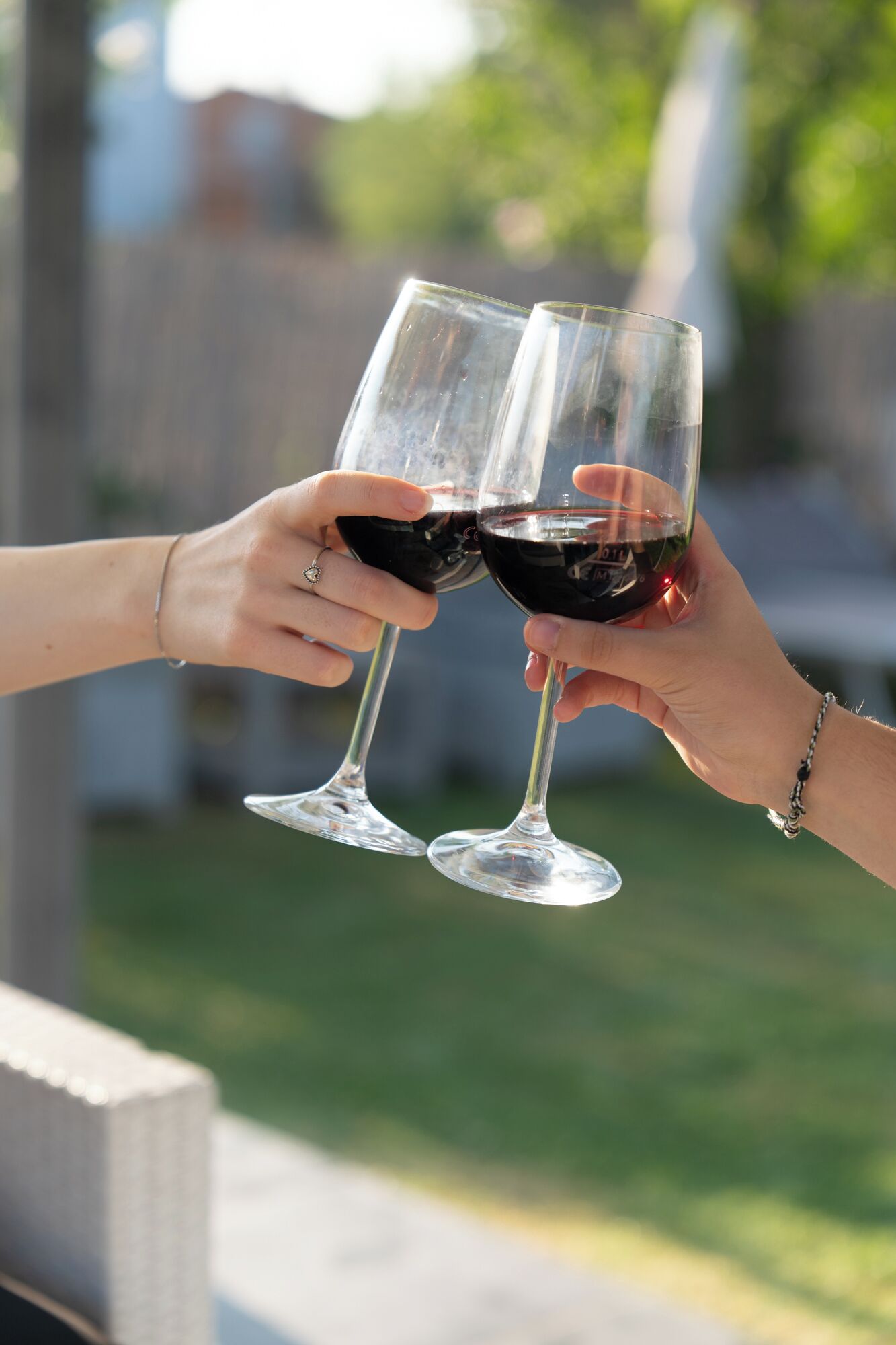 Dos manos sostienen copas de vino tinto, brindando.