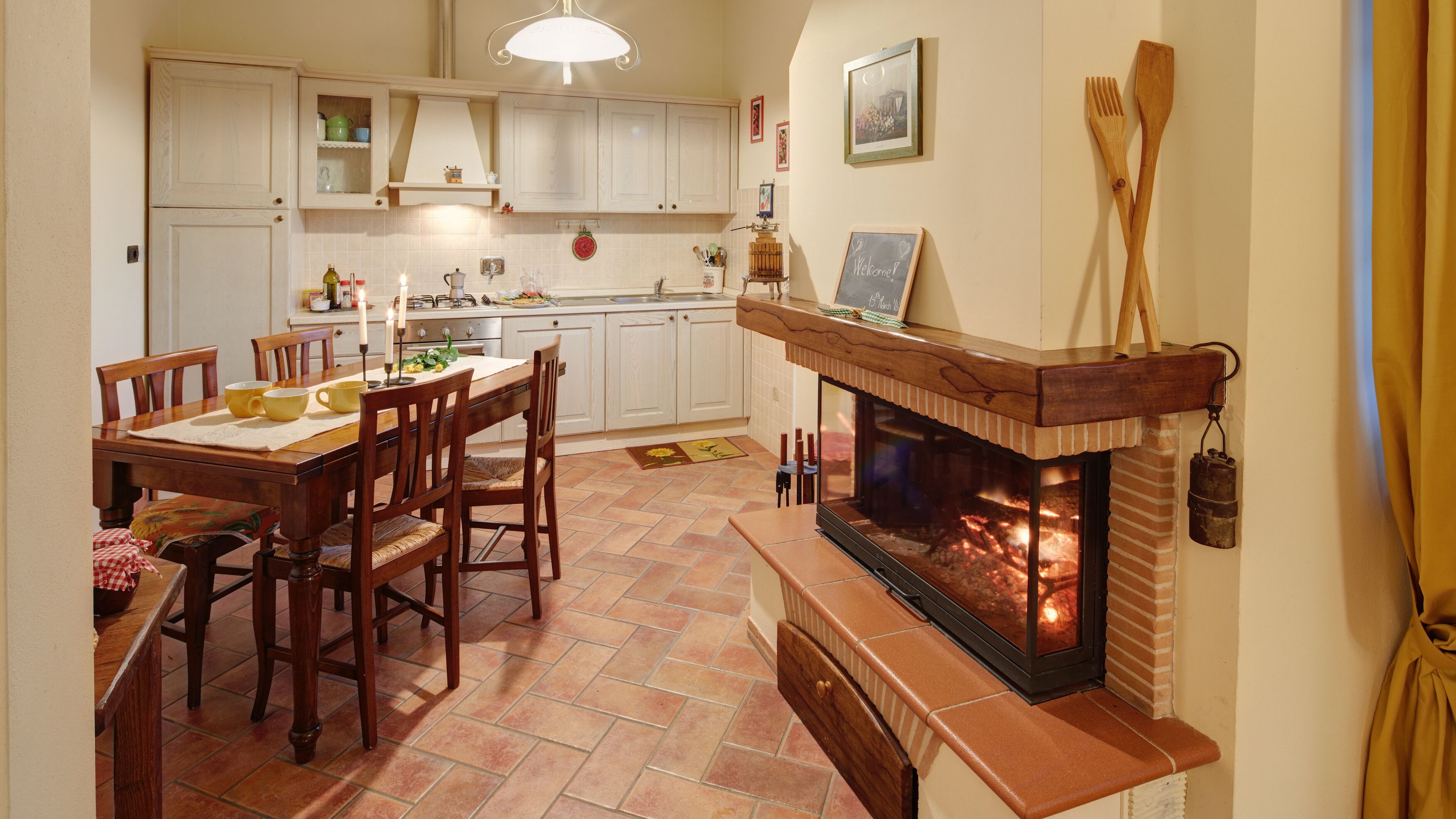 A cozy kitchen with a fireplace, wooden dining table, and chairs.