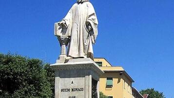Eine Statue eines Mannes in einer Robe mit einem Sockel, auf dem 'GUIDO MONACO 1882' steht.