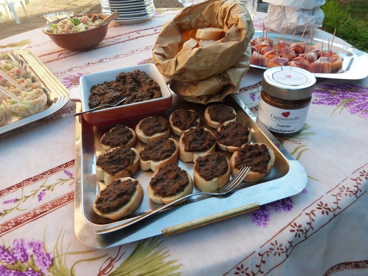Ein Tisch mit Speisen, darunter Brötchen mit Aufstrich, ein Glas Cappuccino-Brotcreme und eine Salatschüssel.