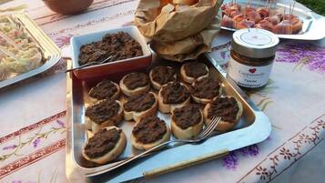Ein Tisch mit Speisen, darunter Brötchen mit Aufstrich, ein Glas Cappuccino-Brotcreme und eine Salatschüssel.