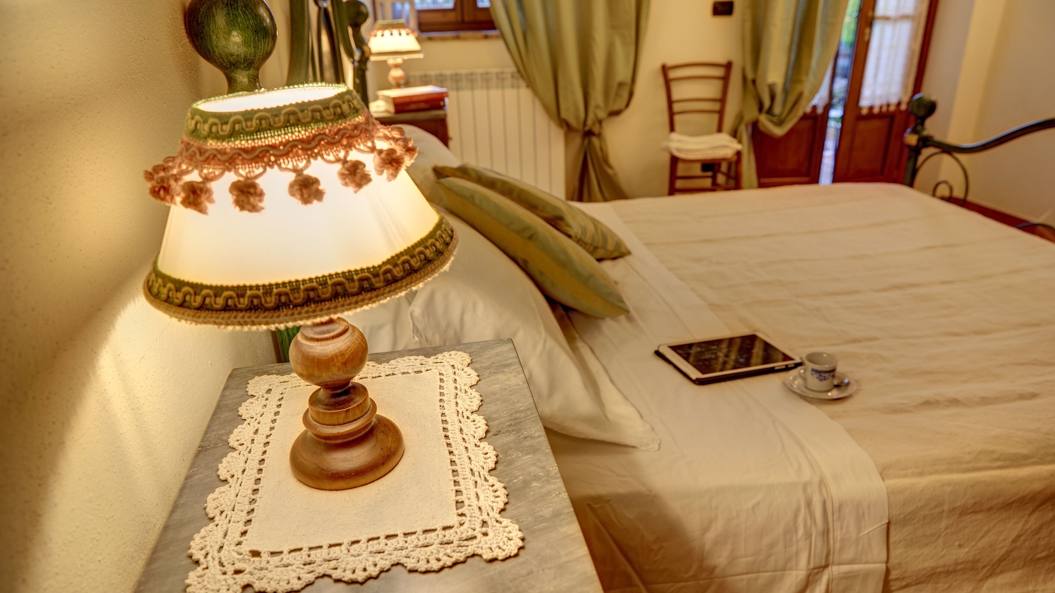 Un lit bien fait, avec une table de chevet, une lampe et une tablette.