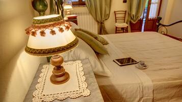 Un lit bien fait, avec une table de chevet, une lampe et une tablette.