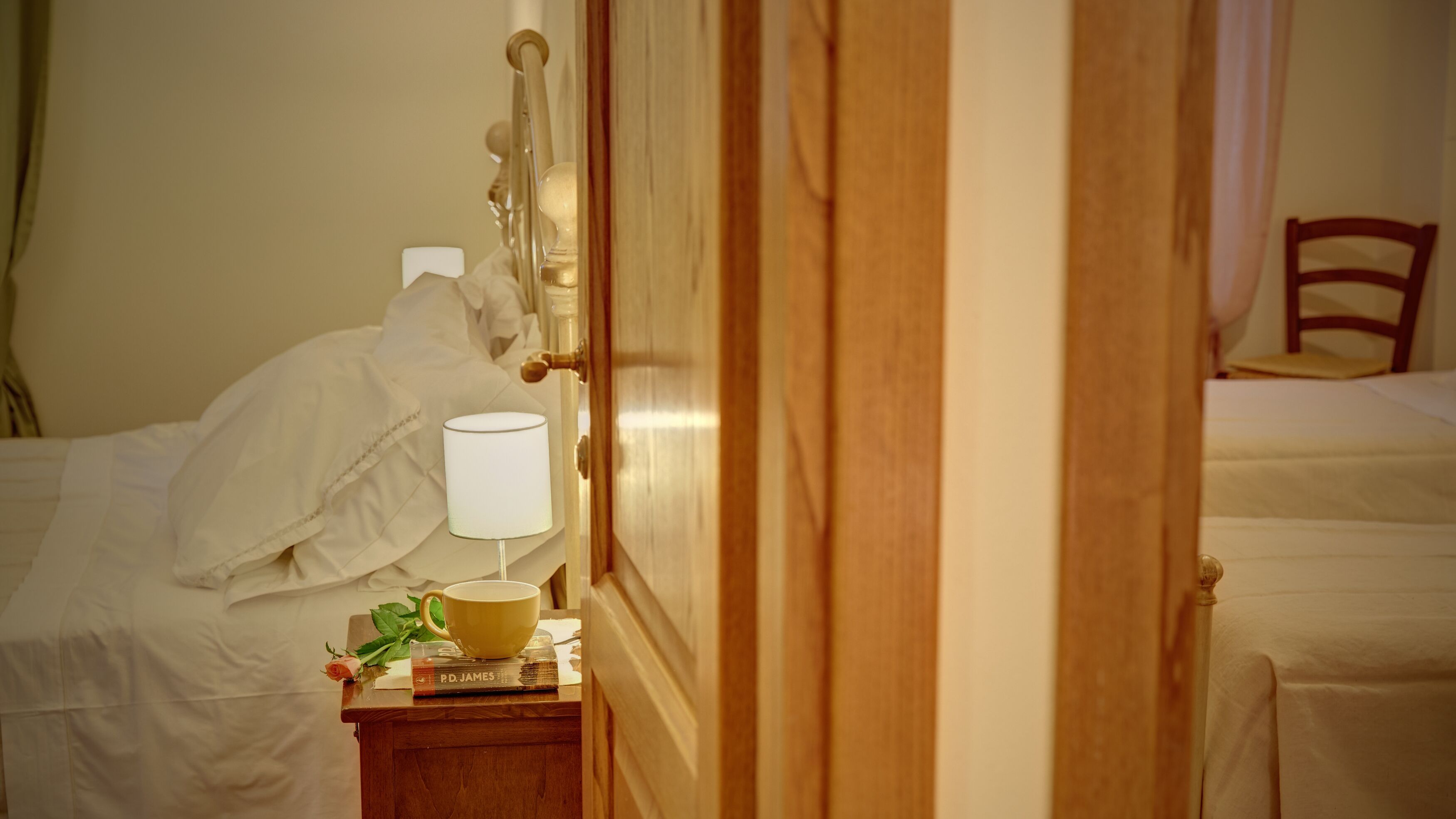 Une chambre d’hôtel avec un lit, une table de chevet avec une lampe, une tasse et un livre.