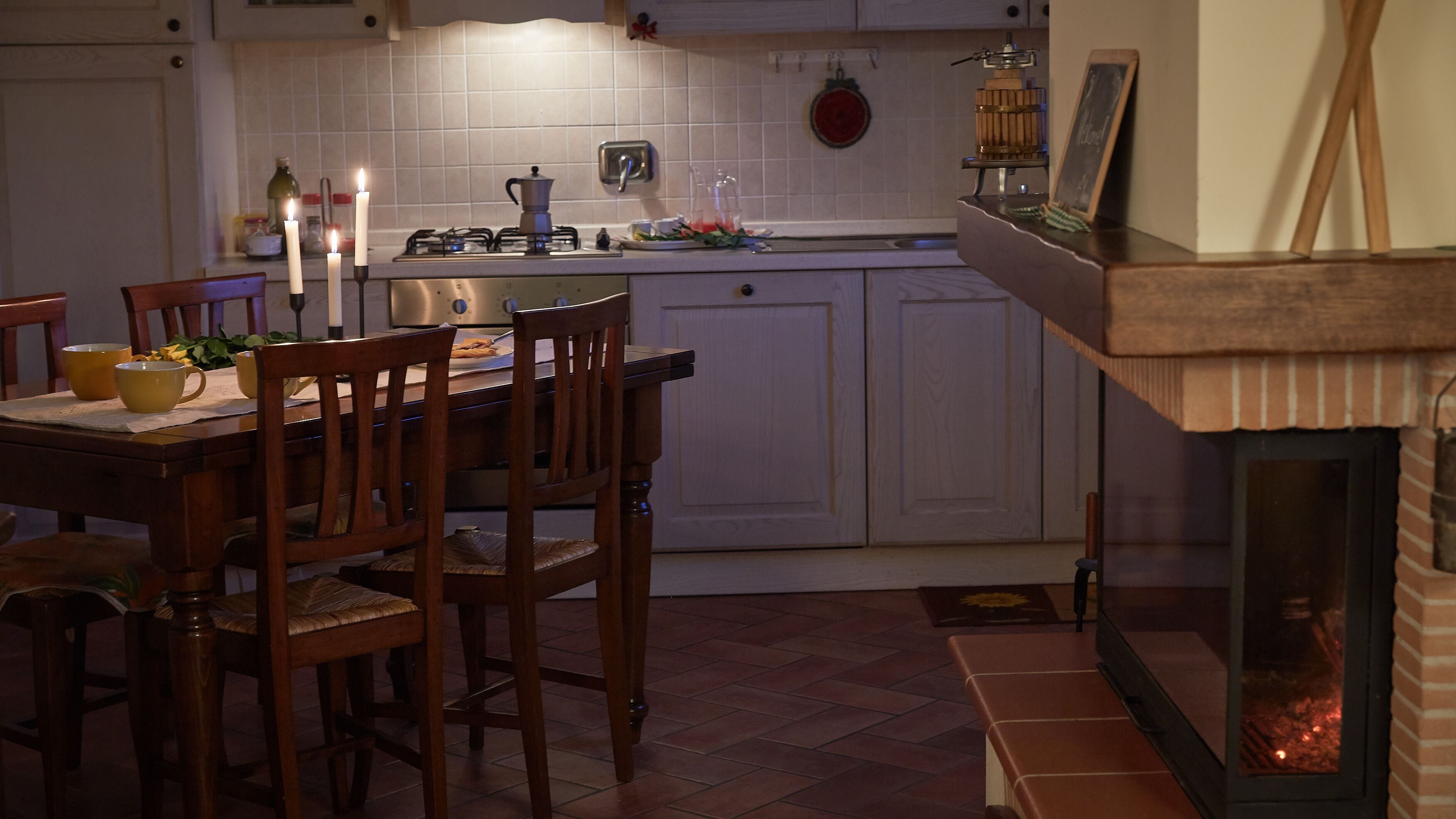 Una cocina con una mesa de comedor, sillas, estufa a gas y chimenea.