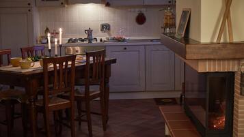 Una cocina con una mesa de comedor, sillas, estufa a gas y chimenea.