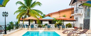 Una piscina al aire libre, sombrillas, sillones reclinables de piscina