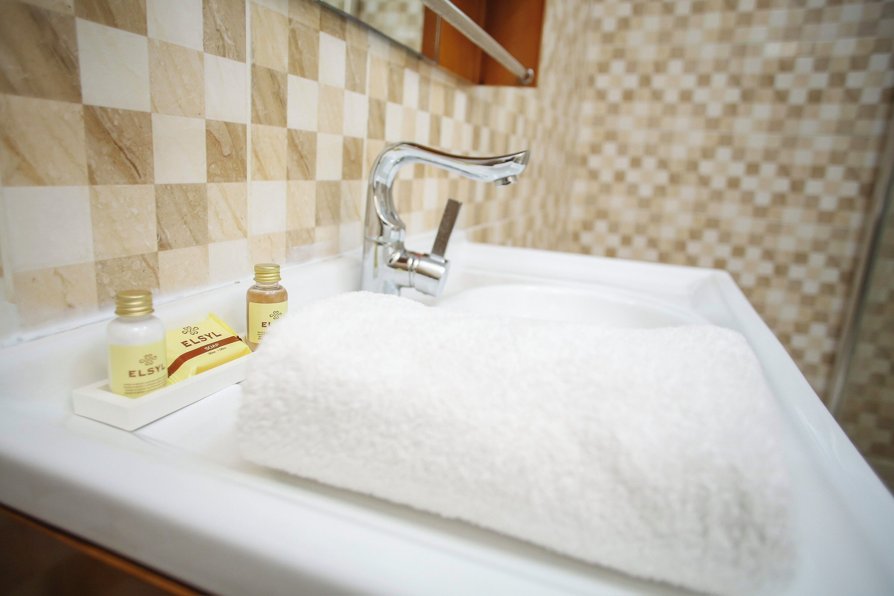 A bathroom with a white sink, a chrome faucet, and toiletries on the counter.