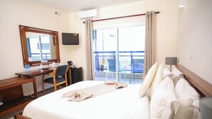 Ein Hotelzimmer mit Bett, Schreibtisch, Stuhl, Fernseher und einem Balkon mit Blick.