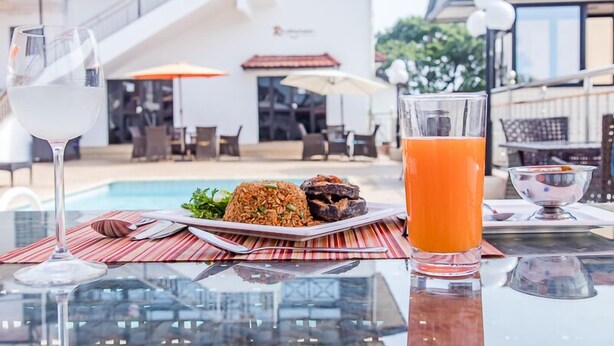 Ein Esstisch mit einem Teller Essen, einem Glas Weißwein und einem Glas Orangensaft.