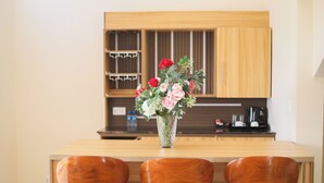 Eine Küche mit Holzschränken, einem Holztisch und drei Holzstühlen. Auf dem Tisch steht eine Vase mit Blumen.