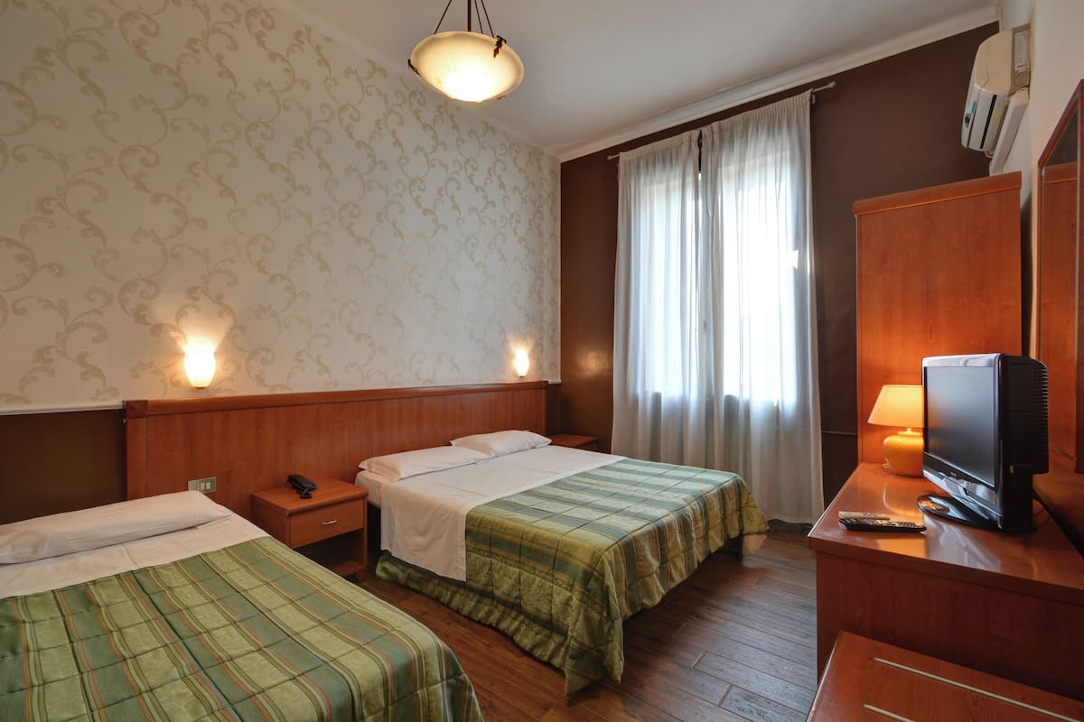 A hotel room with two beds, a television, and a nightstand with a phone.