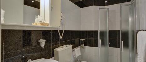 A modern bathroom with a bathtub, two sinks, a toilet, and a glass-enclosed shower.