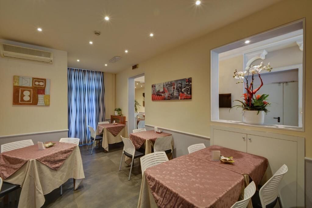 A dining area with tables covered in pink tablecloths, white chairs, and a large window with a view.