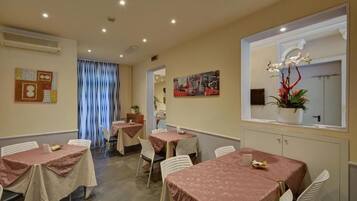 A dining area with tables covered in pink tablecloths, white chairs, and a large window with a view.