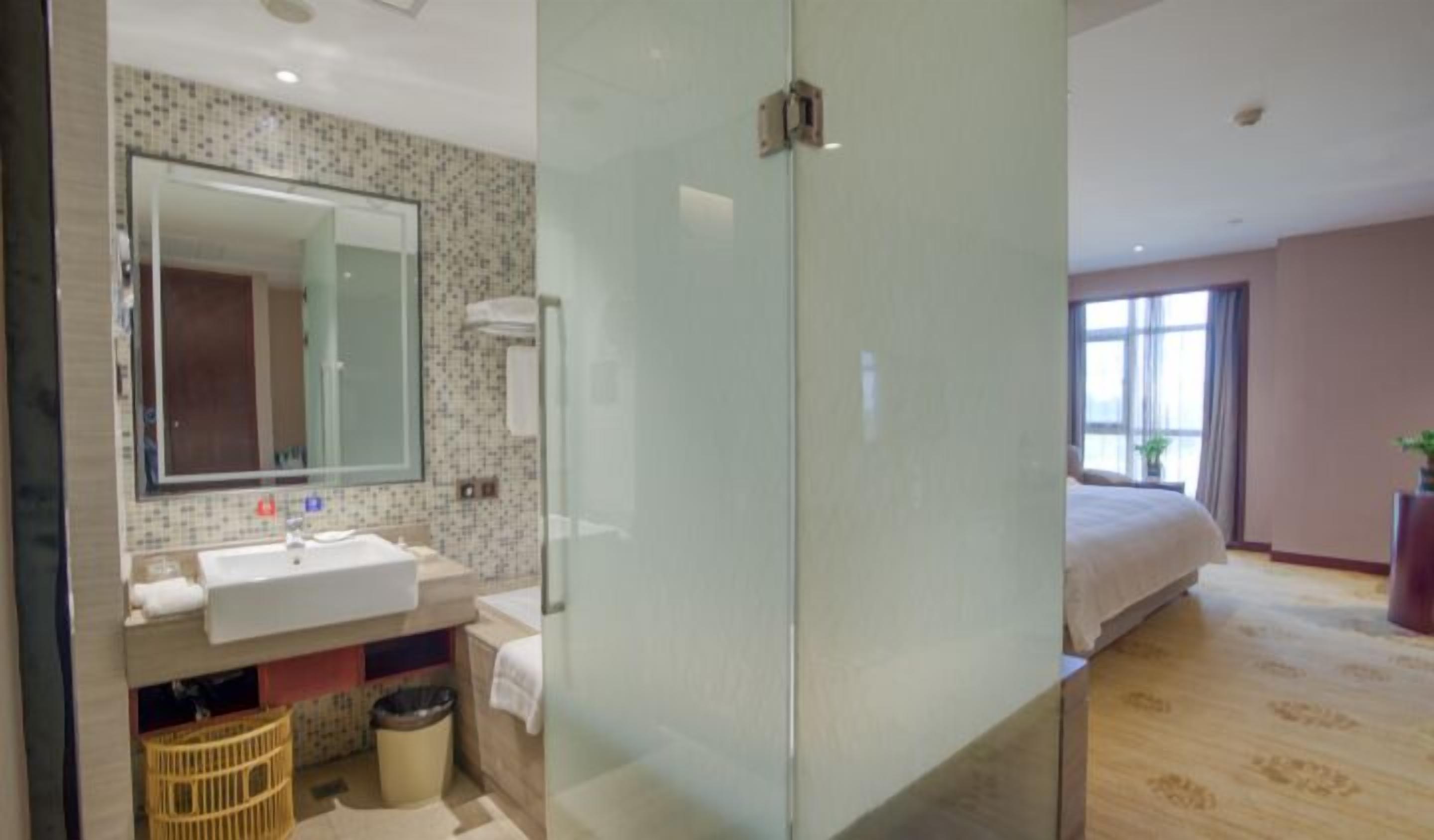 A modern hotel bathroom with a large mirror, sink, and shower area.