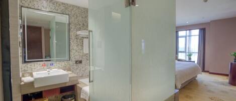 A modern hotel bathroom with a large mirror, sink, and shower area.