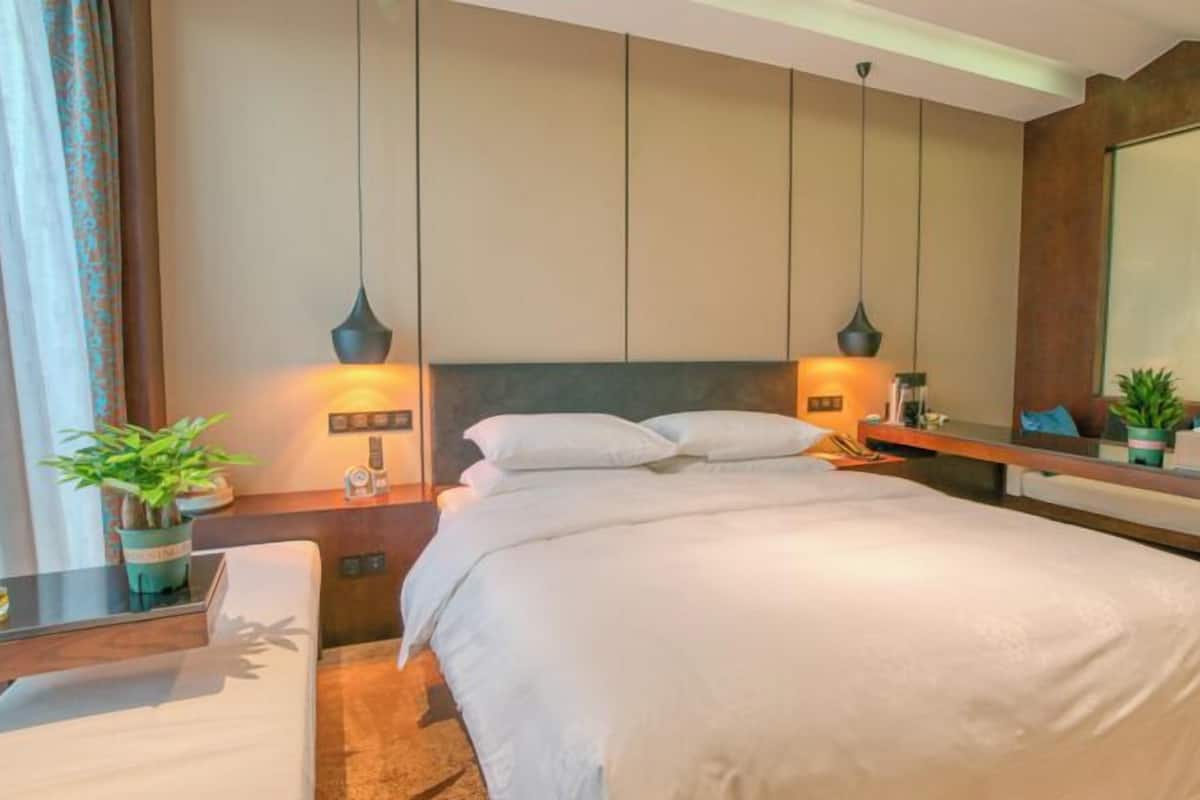 Une chambre d’hôtel avec un grand lit, des tables de chevet, un bureau et un miroir.