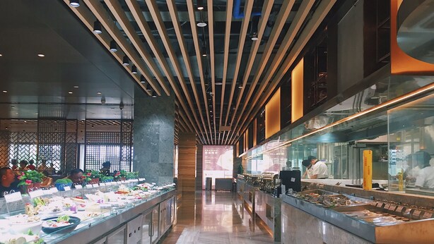 Un espace buffet doté d’un long comptoir, d’un éclairage suspendu et d’un aménagement intérieur moderne.